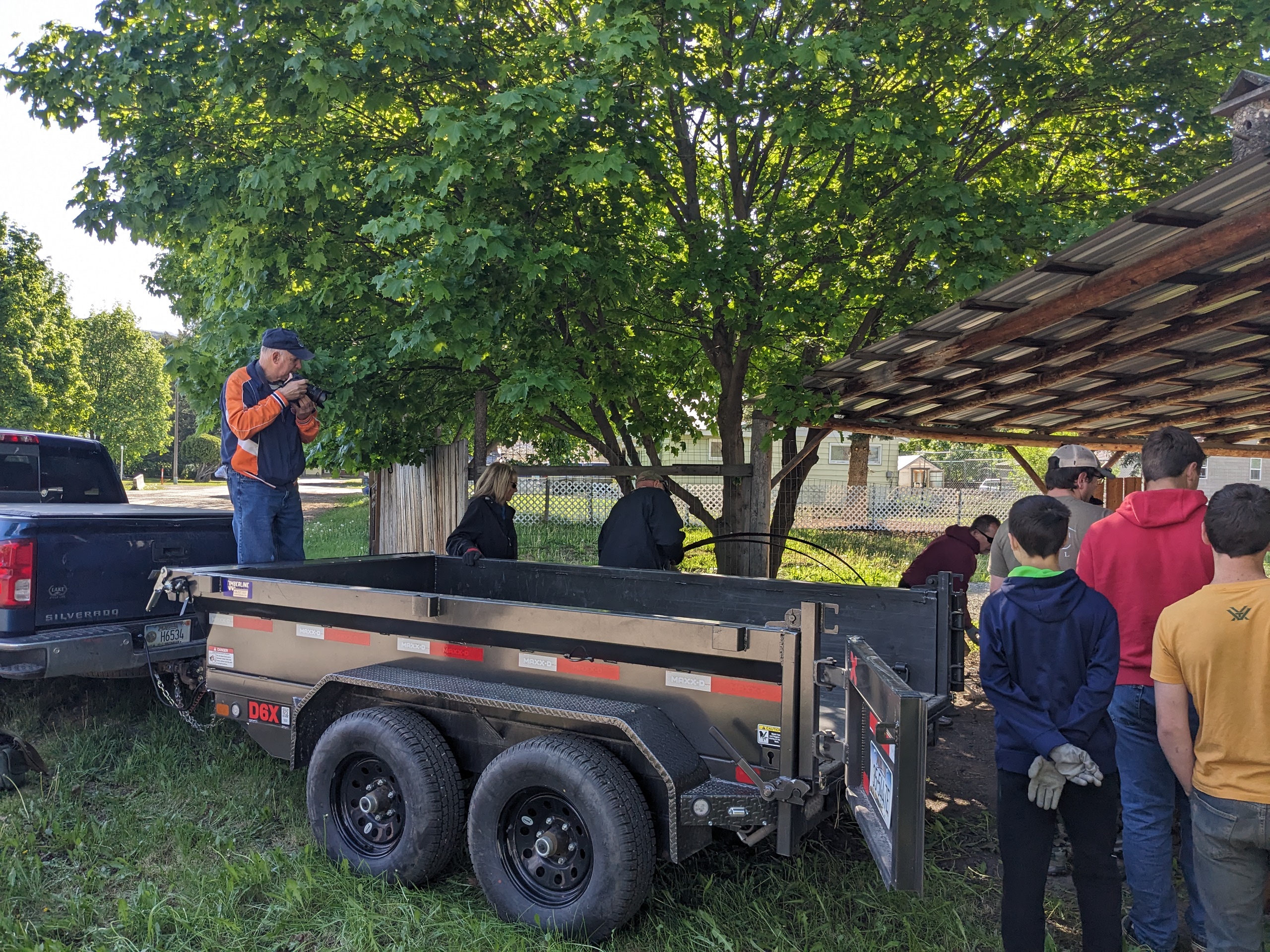 Volunteers bagging leaves and trash in a tulip-bordered yard